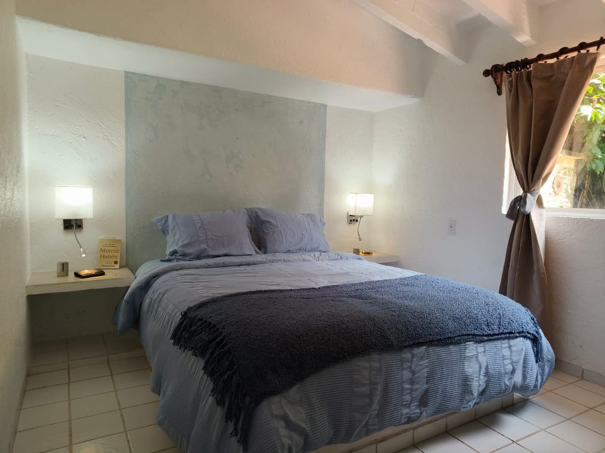 Recámara del Bungalow 1: cama matrimonial con lámparas de lectura y ventana al jardín
