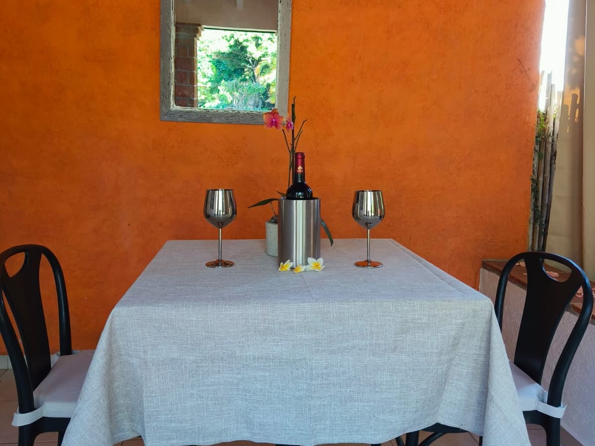 Terraza del Bungalow 2: mesa para dos con copas y vino junto a la pared naranja