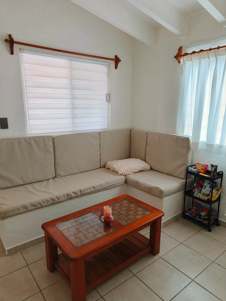 Sala del Bungalow 2 con sillón esquinero, mesa de centro de madera y el carrito del mini súper