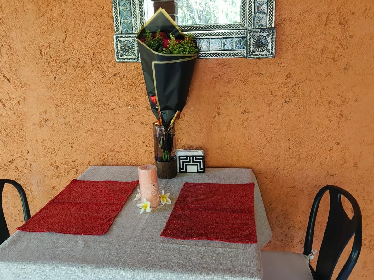 Mesa en la terraza con manteles rojos, flores y un ramo de rosas